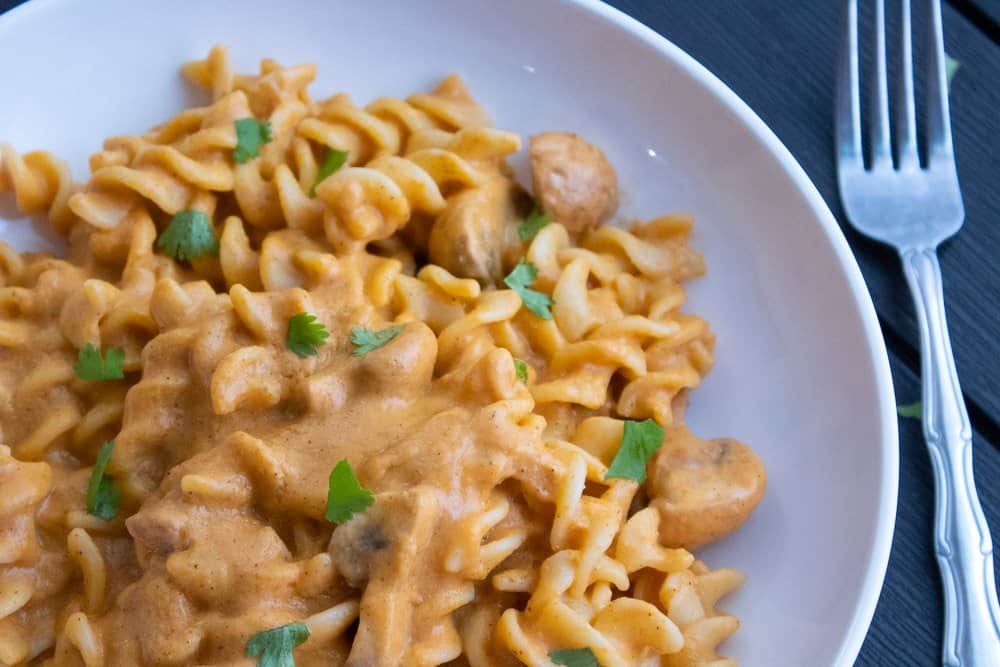 Instant pot creamy tomato cashew pasta served on a white plate with a fork on the side.