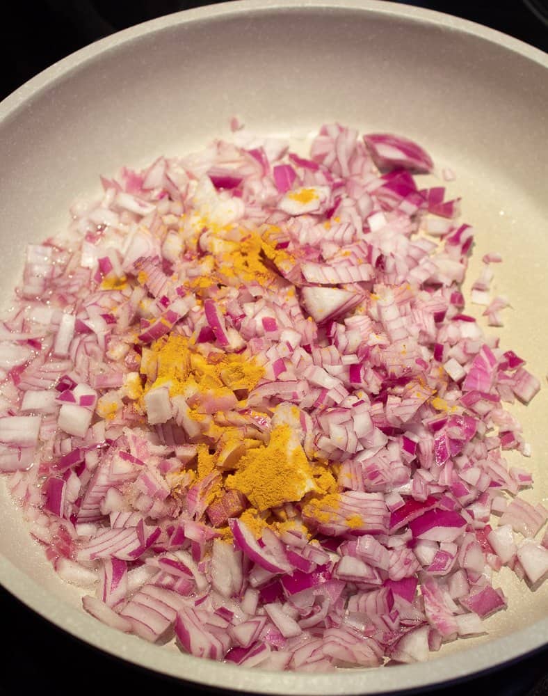 Added chopped onions to the hot oil, with turmeric and salt, to saute.