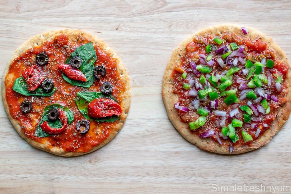 Greek Inspired Pita Pizza and Mexican Inspired Pita Pizza in the middle of the prep before putting cheese on them to cook.
