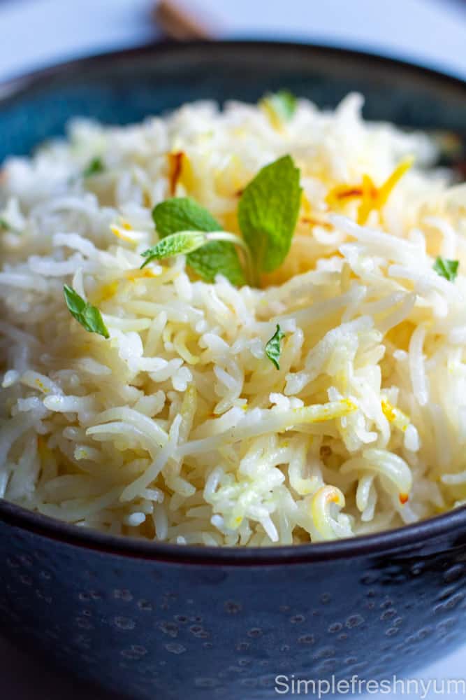 close up picture of cooked Basmati Rice in a black bowl with Mint garnished on top