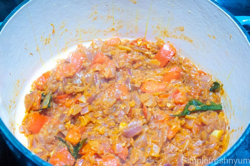 Cooked tomatoes until softened along with onions in the stove top cooking pot