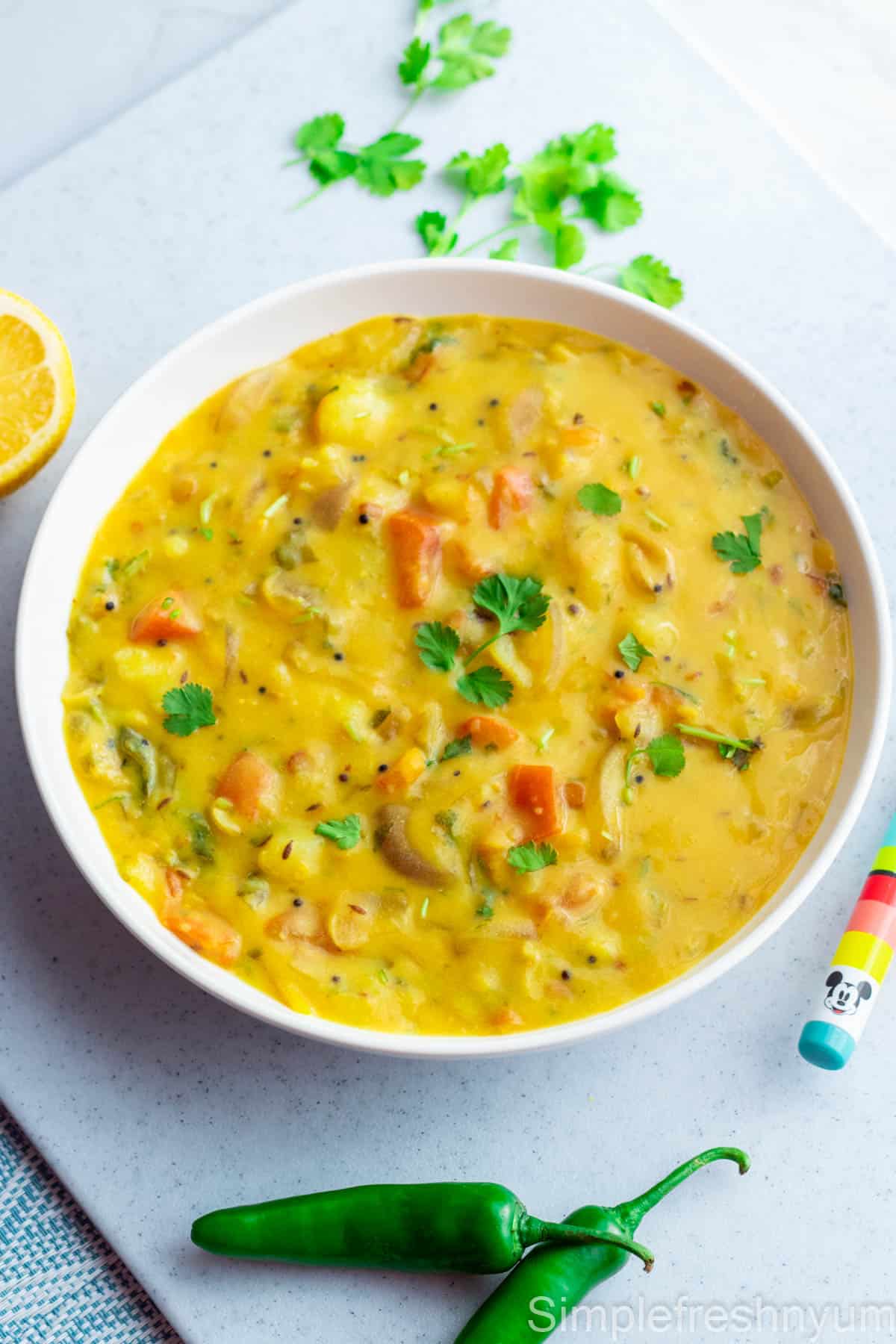 Chutney served in a white serving plate with cilantro, lemon half and jalapenos on the sides.