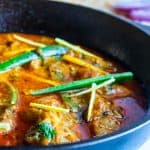 Chicken Karahi served in a black cast iron wok ( Karahi) with slices of jalapenos and ginger juliennes on the top