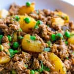 Aloo Kheema Matar served in a white plate with cilantro garnished on top